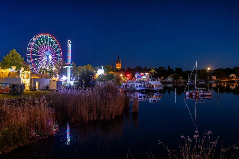 Werder Baumblütenfest bei Nacht mit beleuchtetem Riesenrad und Veranstaltungsgelände am Wasser